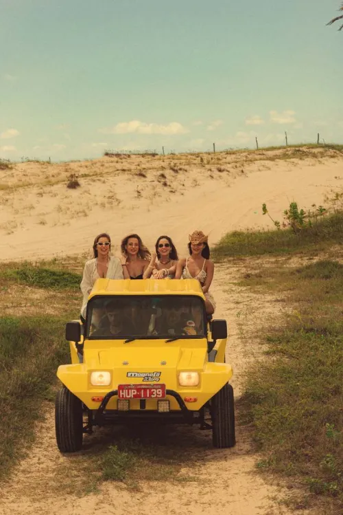 Grupo de amigas em um buggy amarelo nas dunas