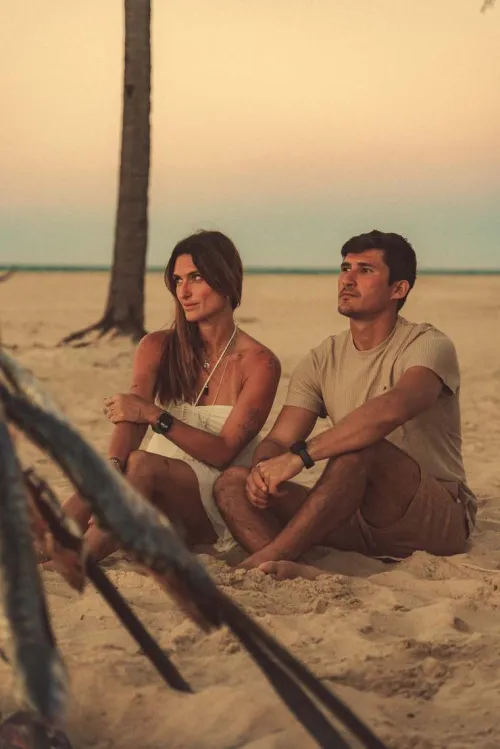 Casal sentado perto da fogueira ao entardecer